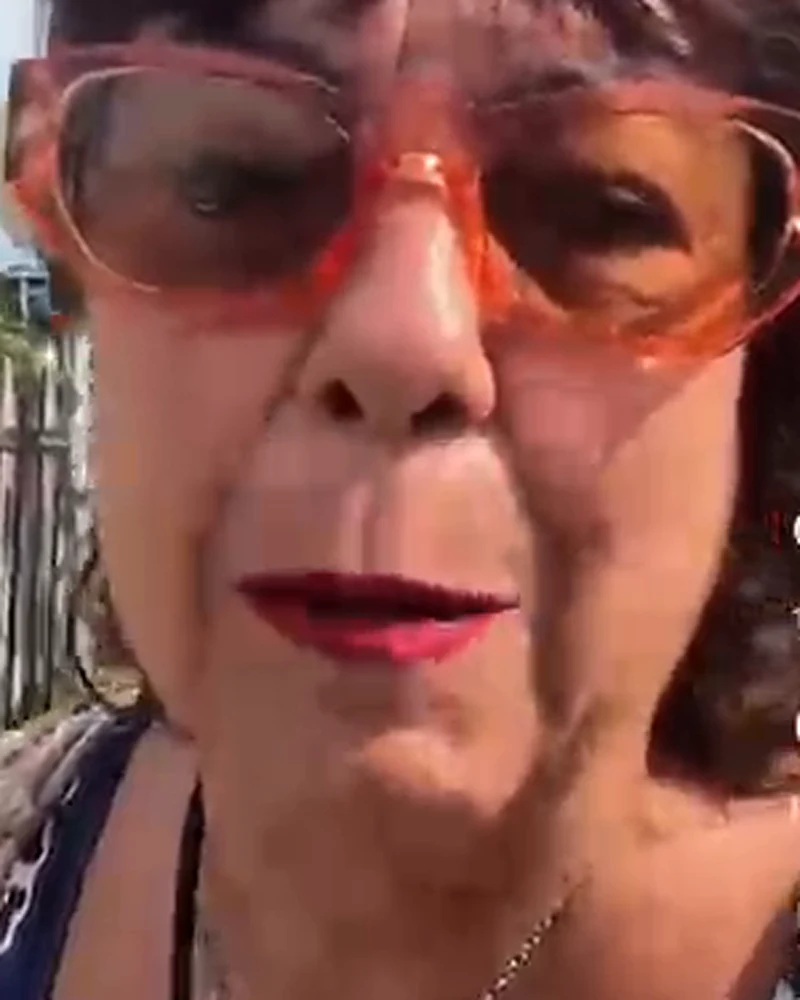 Rachel de óculos coral, animada, falando bem perto da câmera