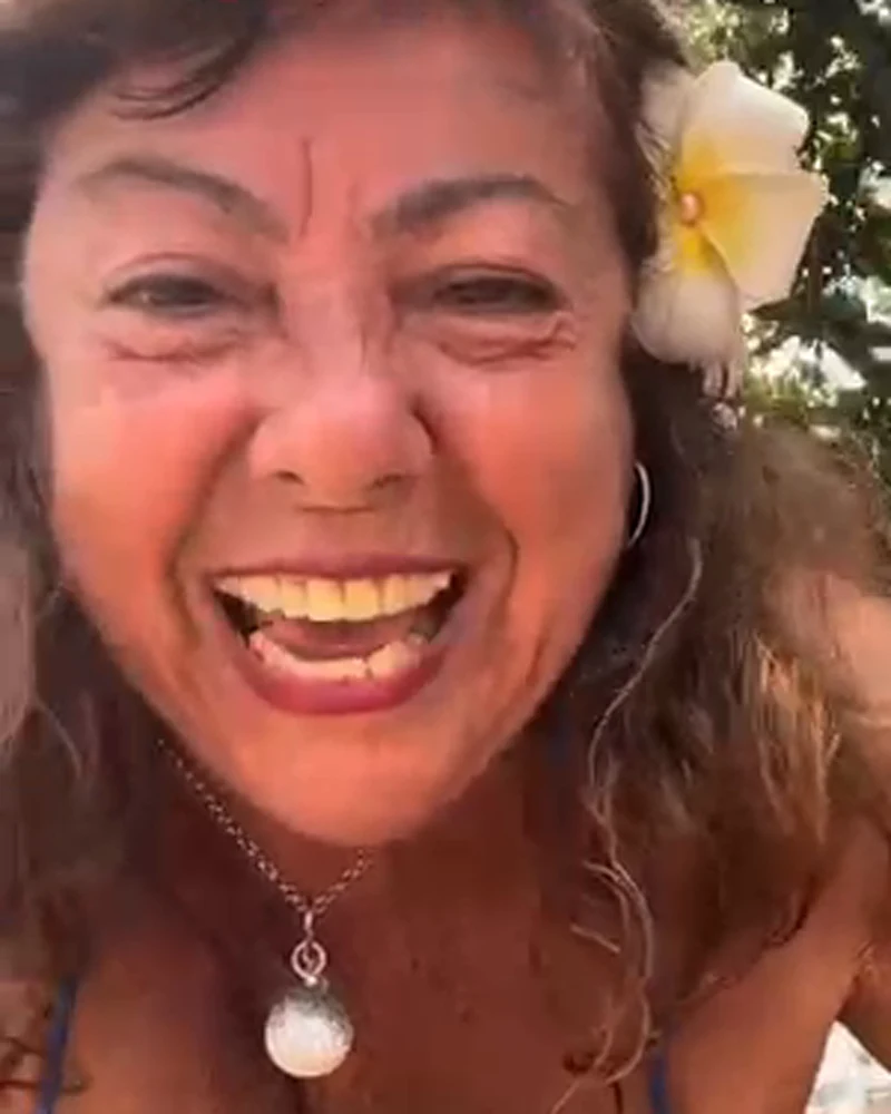 Rachel gargalhando com uma flor branca no cabelo
