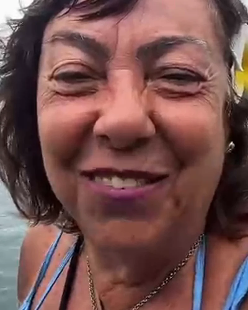 Rachel rindo com flor no cabelo, na praia